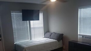 Un dormitorio con una cama, un ventilador de techo y un aparador.