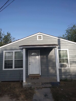 A single-story house with a front door, two windows, and a small porch. - Tranquil 2-bedroom house with AC in Orange Grove (Orange Grove)