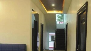 A hotel corridor with a reception area, a sofa, and a staircase.