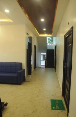 A hotel corridor with a reception area, a sofa, and a staircase. - RATHNA RESIDENCY YERCAUD (Yercaud)