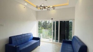 A room with two blue sofas, a ceiling light fixture, and a view through a glass door.