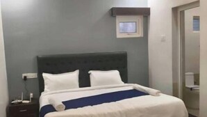 Un dormitorio con cama, ventilador de techo, mesita de noche y televisor montado en la pared.
