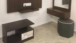A bathroom with a mounted TV, a large mirror, and a vanity with a sink.