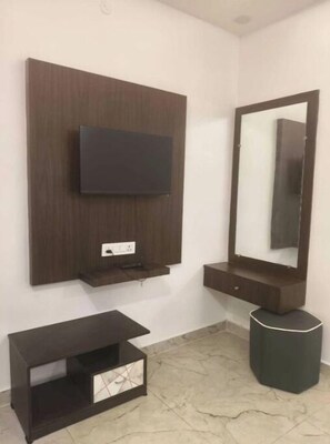 A bathroom with a mounted TV, a large mirror, and a vanity with a sink. - RATHNA RESIDENCY YERCAUD (Yercaud)