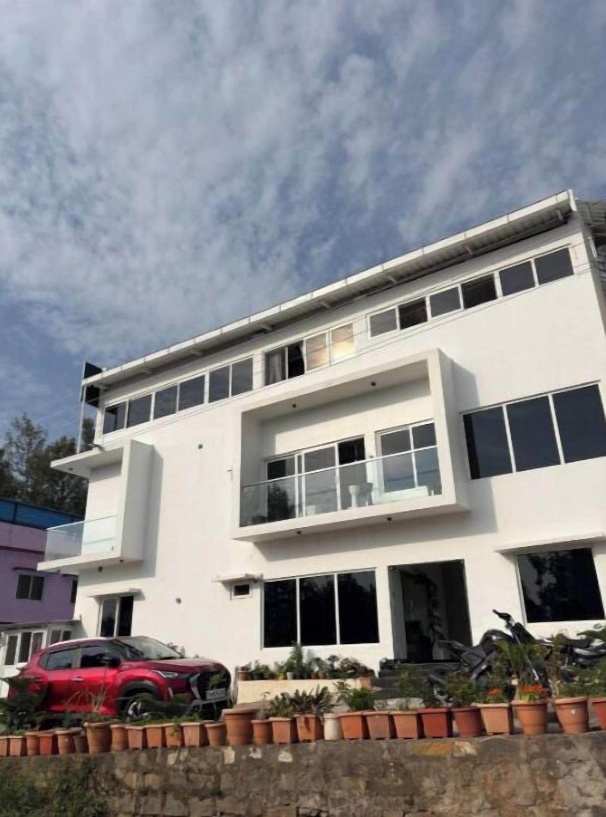 A modern two-story building with a flat roof, large windows, and a balcony.