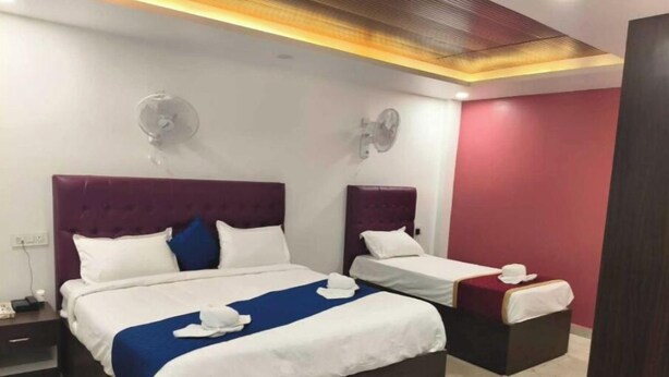 A hotel room with two beds, a nightstand, a wall clock, and a ceiling fan.