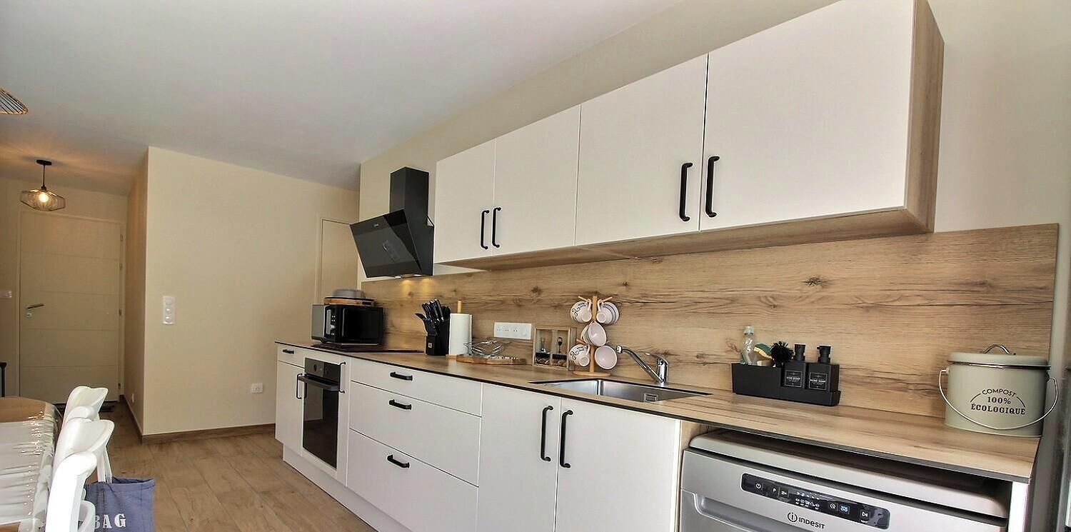 Een moderne keuken met witte kastjes, een magnetron, een spoelbak en een vaatwasser.