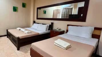 A hotel room with two beds, a large mirror, and a small bedside table with a lamp.