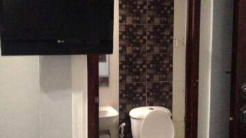 A bathroom with a toilet, sink, and a mounted television.