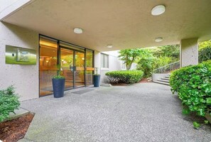 A building entrance with a glass door, a potted plant, and a staircase leading to an upper level.
