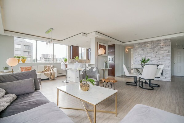 A modern living room with a sofa, coffee table, and dining area with chairs and a table.