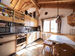 Eine Küche mit Holzausstattung, einem Herd und einem Essbereich mit Tisch und Stühlen.