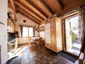 A cozy kitchen with wooden cabinets, a dining table with chairs, and a large window.