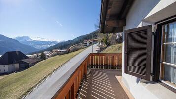Un balcon offrant une vue sur une chaîne de montagnes et un ciel dégagé.