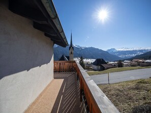Un balcon avec vue sur une église et des montagnes enneigées.