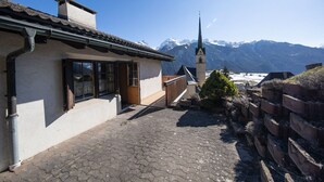 A building with a traditional design, a paved courtyard, and a mountain backdrop. - 2001 Haus Alvaneu by Interhome (Alvaneu Dorf)