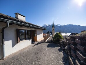 Ein Gebäude im traditionellen Stil, ein gepflasterter Innenhof und eine Bergkulisse im Hintergrund.