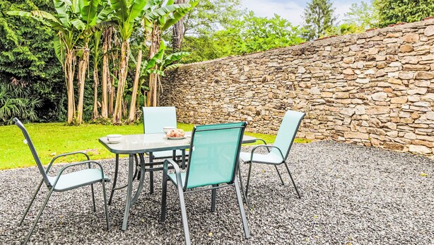 Un patio al aire libre con un muro de piedra, una mesa y sillas.