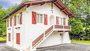 Un edificio blanco con contraventanas rojas, un balcón y una escalera que conduce a la entrada.