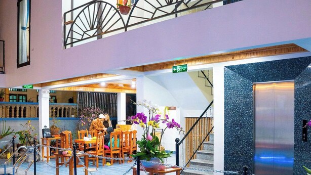 Ein Innenpool mit Schachbrettmuster, eine Holzterrasse mit Stühlen, eine Treppe und ein Metallgeländer.
