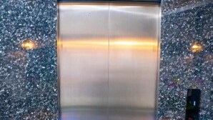 Ein Aufzug mit metallischer Innenausstattung und einer grünen Matte am Boden.