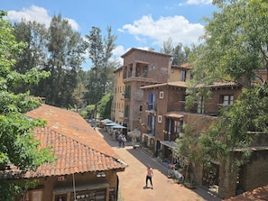 A street with buildings, a person rollerblading, and trees. - Departamento Raziel 118 (Val'Quirico)