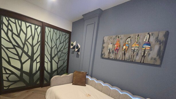 A room with a sofa, a decorative wall piece, and a sliding door with a tree pattern. - Departamento Raziel 118 (Val'Quirico)
