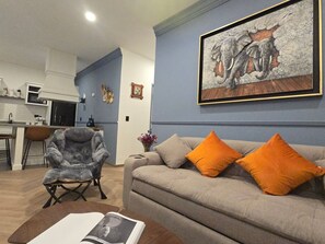 Una sala de estar con un sofá, un sillón y un cuadro en la pared.