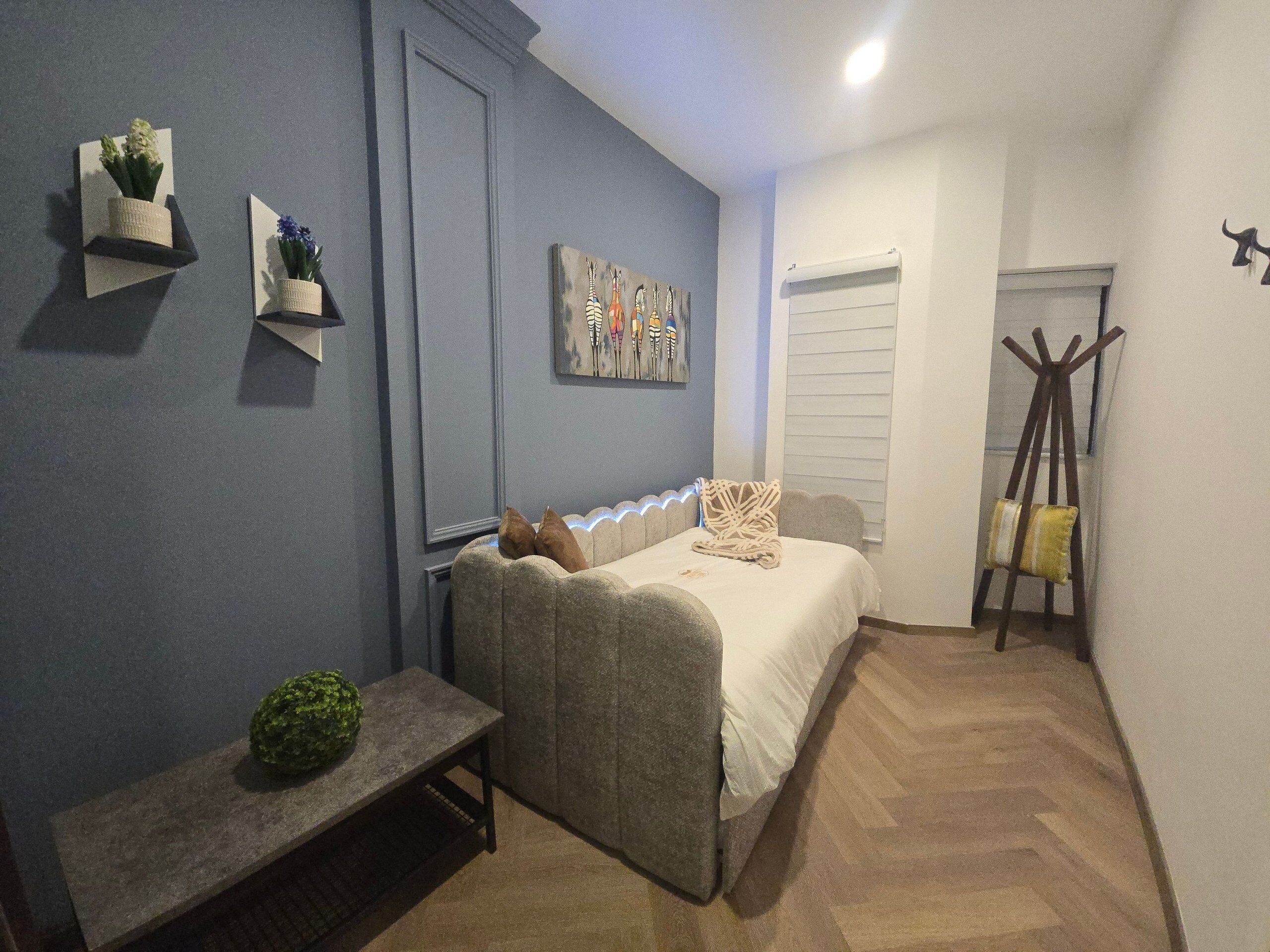 Ein Schlafzimmer mit Bett, Nachttisch und einer kleinen Pflanze.