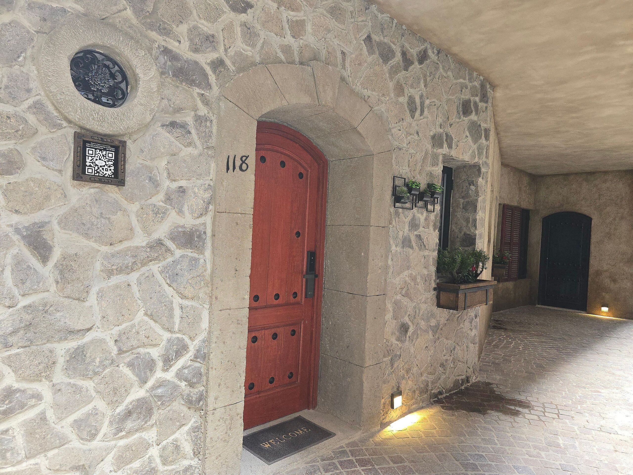 Un edificio de piedra con una puerta roja, un código QR y un felpudo.