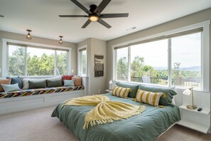 Ein Schlafzimmer mit einem großen Bett, einer Sitzbank unter dem Fenster und einem Deckenventilator.