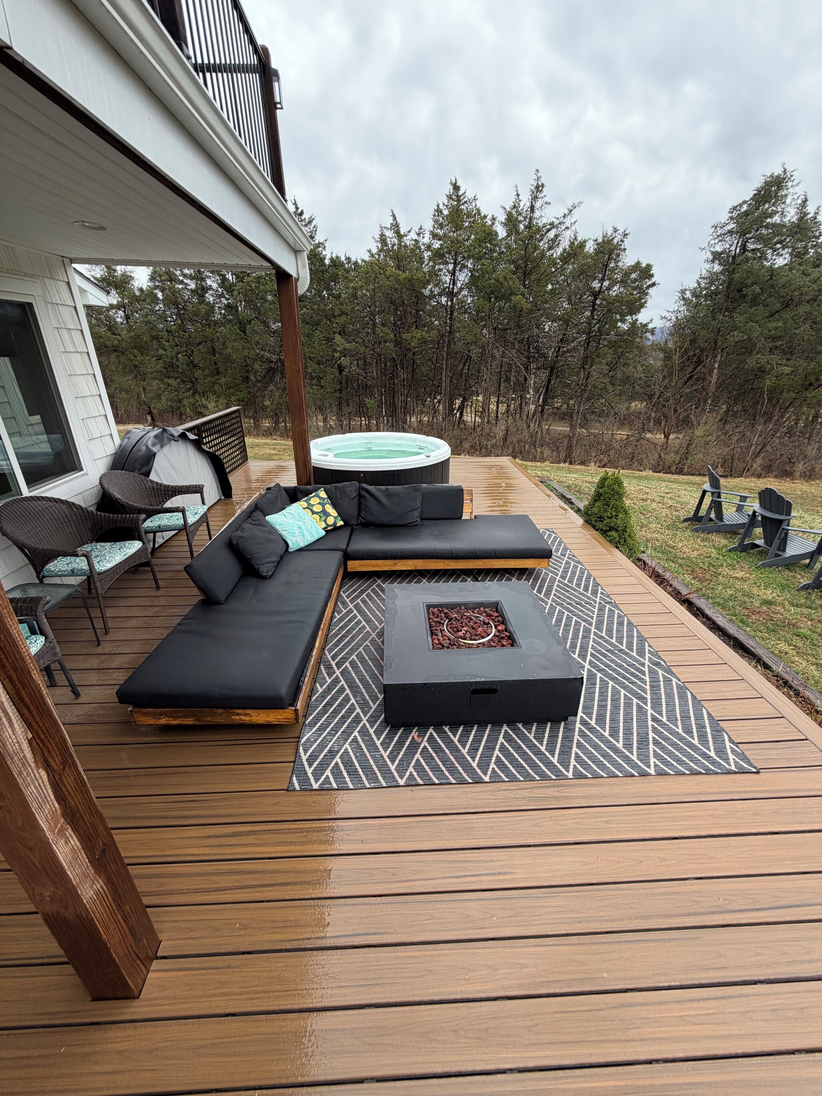 A deck with a sofa, chairs, and a hot tub.