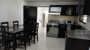 A kitchen with a dining table, chairs, a stove, microwave, and cabinets.