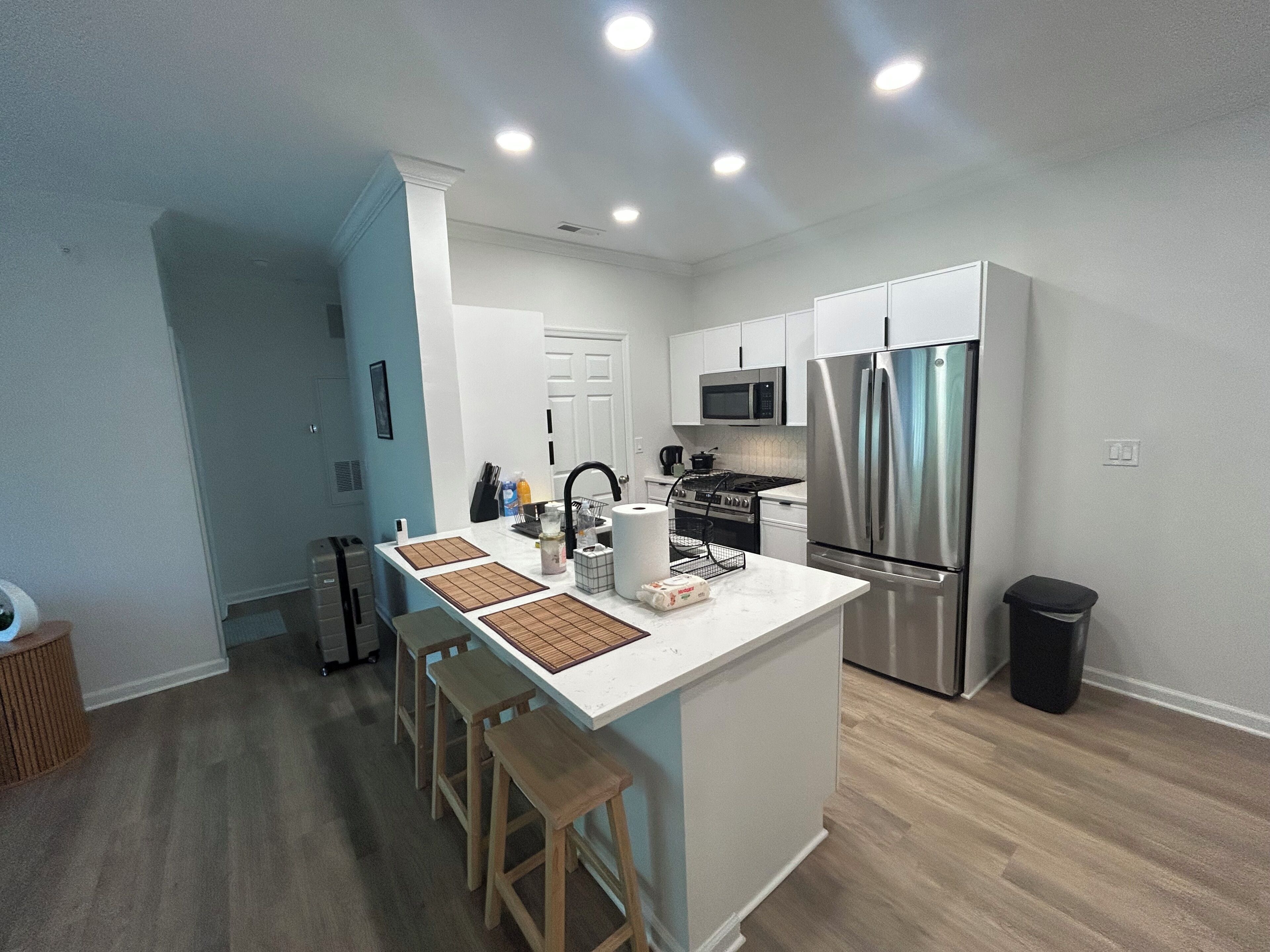 A modern kitchen with a central island, stainless steel appliances, and wooden stools.