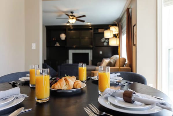 Une table mise pour le petit-déjeuner, avec une nappe pour deux personnes, des croissants et des verres pour le jus d’orange.