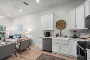 A modern kitchen with white cabinetry, a built-in dishwasher, a coffee maker, and a microwave.