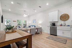 A modern kitchen with white cabinets, a dishwasher, and a coffee maker.