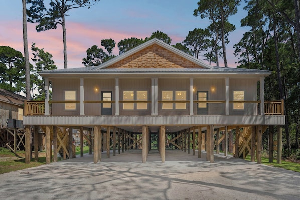 A two-story house with a balcony, wooden deck, and a view of the surrounding trees.