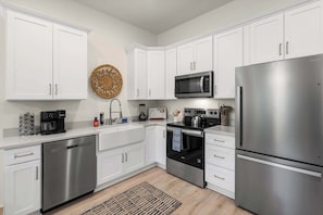 A modern kitchen with white cabinets, stainless steel appliances, and a patterned rug.