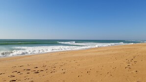 Uma praia com pegadas, ondas e céu claro.