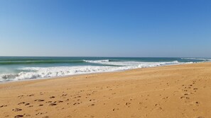 Une plage avec des empreintes de pas, des vagues et un ciel dégagé.