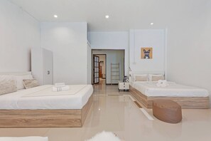 A modern hotel room with two beds, a wooden bench, a fluffy rug, and a painting on the wall. - Coco's Townhouse BTS Onnut 350 Meters 3br3bth (Bangkok)