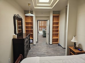 Ein Hotelkorridor mit einem Bett, einem Schminktisch, einem Spiegel, einem Deckenventilator und Holzbögen.