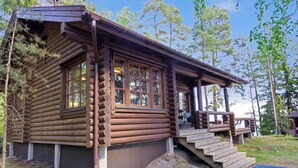 A log cabin with a porch, large windows, and a staircase leading up to the entrance. - Kariniemi by Interhome (Lohja)