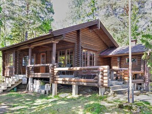 A log cabin with a porch, large windows, and a chimney.