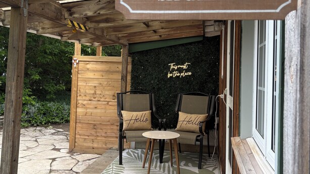Eine hölzerne Veranda mit einem Schild, auf dem 'THE PORCH SIT & RELAX' steht.