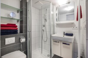 Une salle de bain moderne avec une douche à parois de verre, un lavabo blanc et des toilettes.