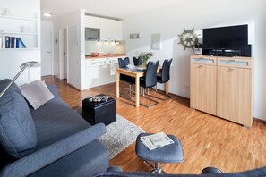 Un salon moderne avec un canapé gris, une table basse et un téléviseur posé sur un meuble en bois.