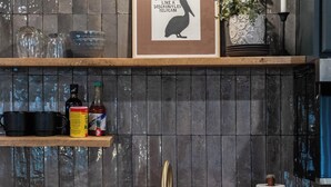 Una cocina con encimera de madera, un lavamanos, un cuadro enmarcado y una planta en maceta.