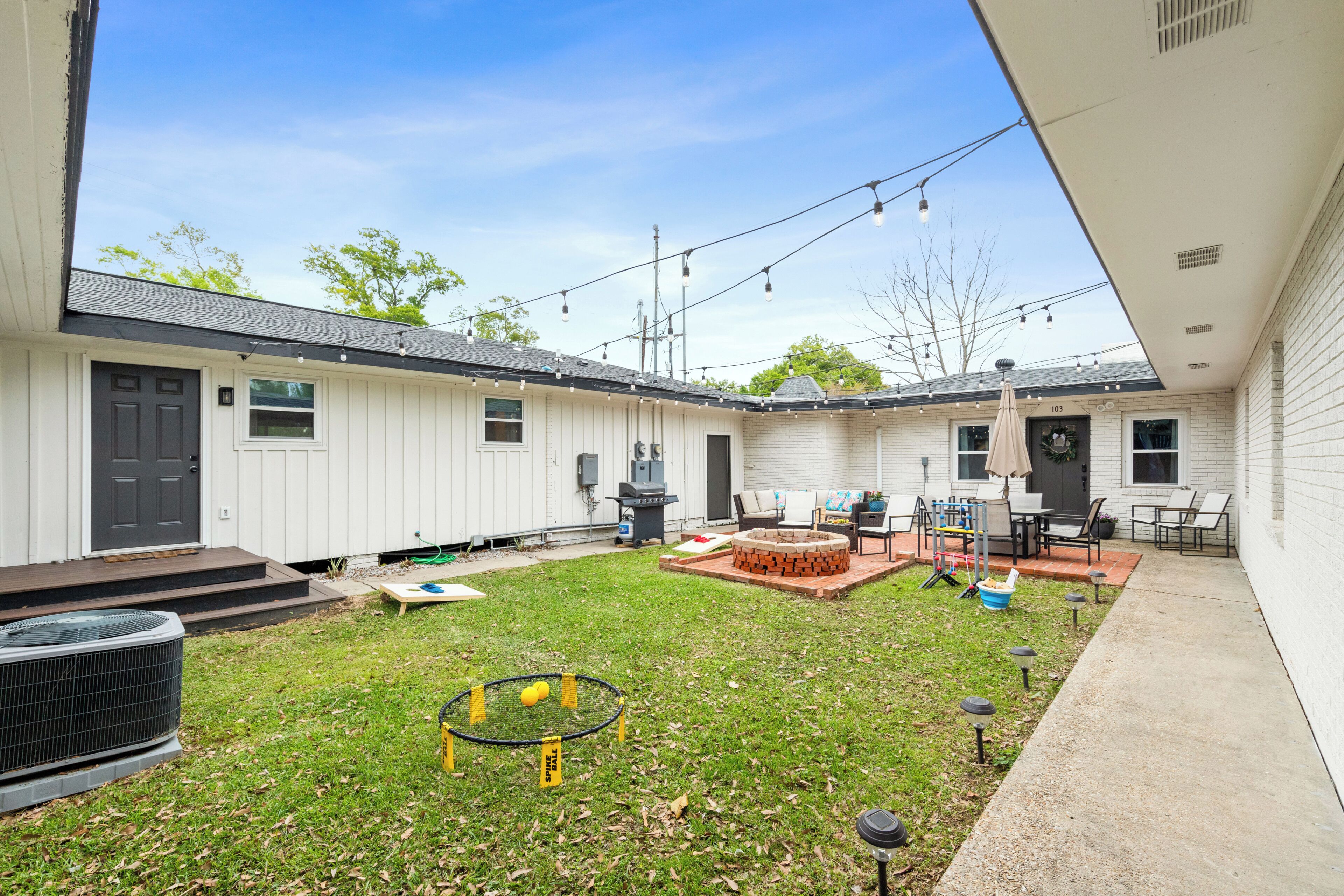 A backyard with a fire pit, outdoor seating, and a string of lights.